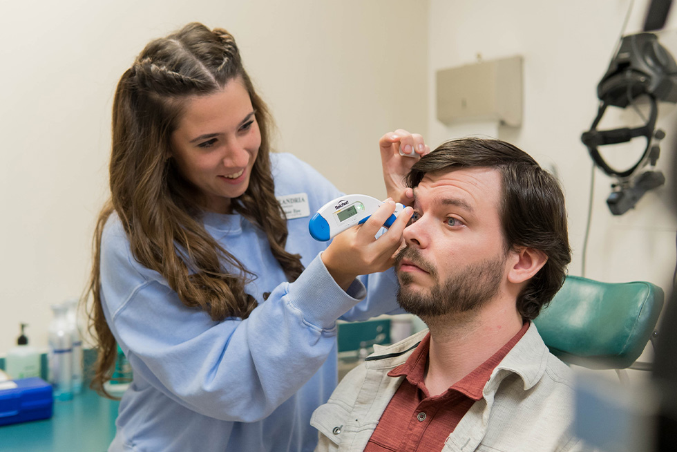 A nurse smiles and checks a patient's eye pressure