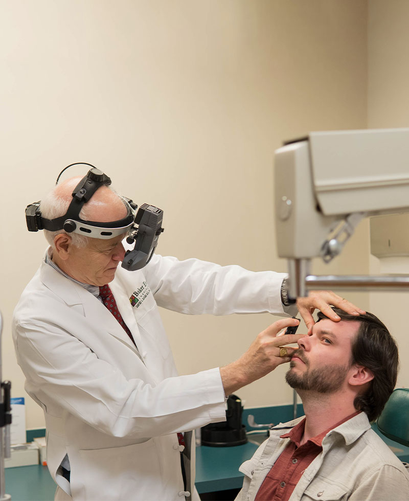 dr baker looks into a patient's eyes using a very interesting looking apparatus on his head to help him see better